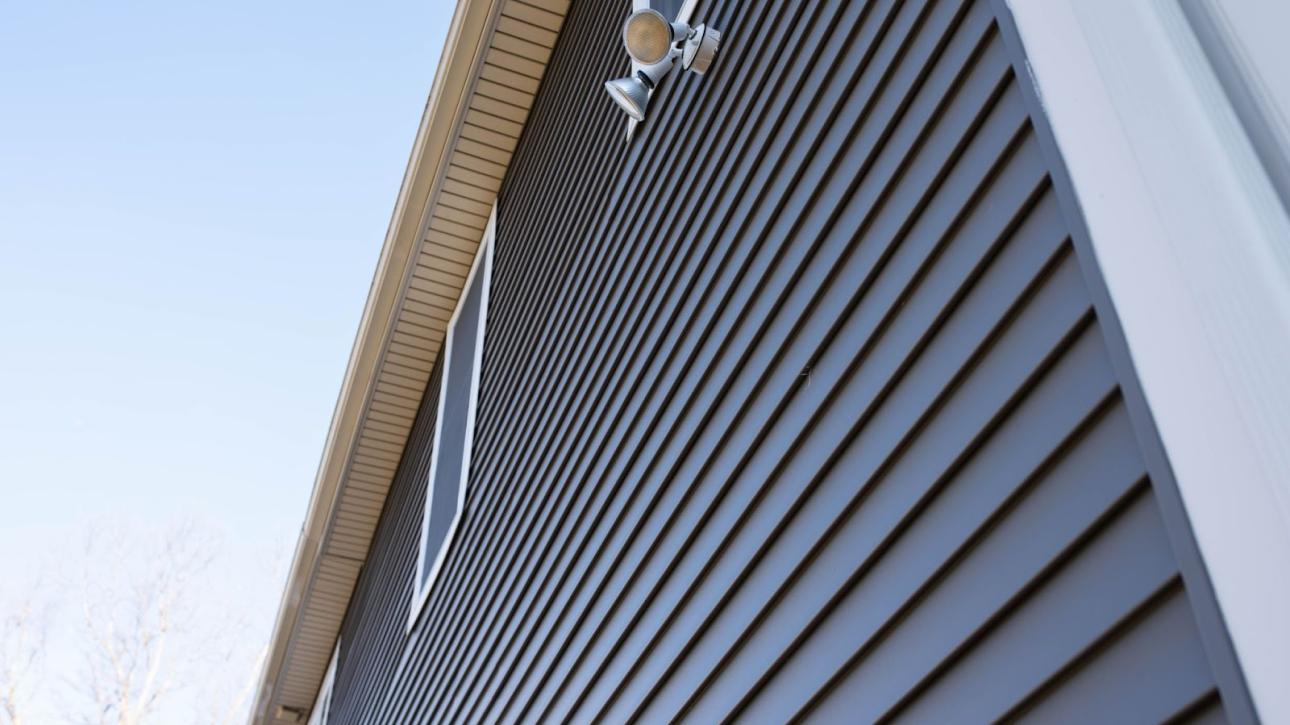 Upward view of a house with gray vinyl siding and white trim