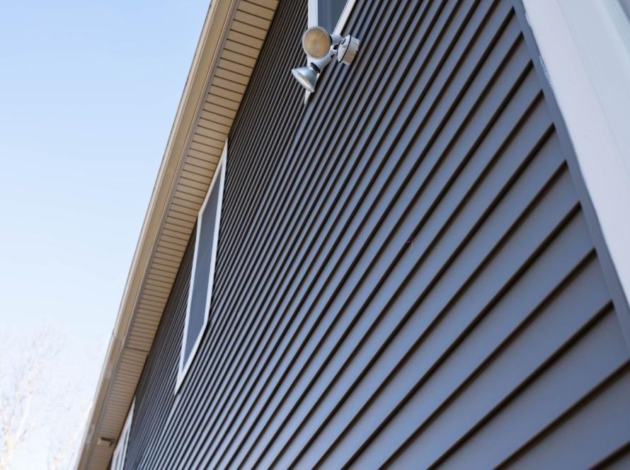 Upward view of a house with gray vinyl siding and white trim