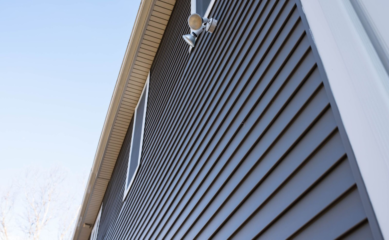 Upward view of a house with gray vinyl siding and white trim