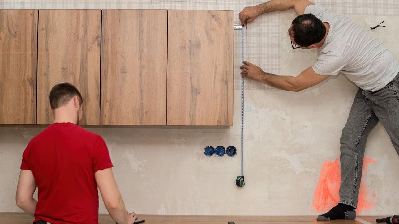 Two kitchen installation specialists measuring cabinetry for a modern kitchen remodel