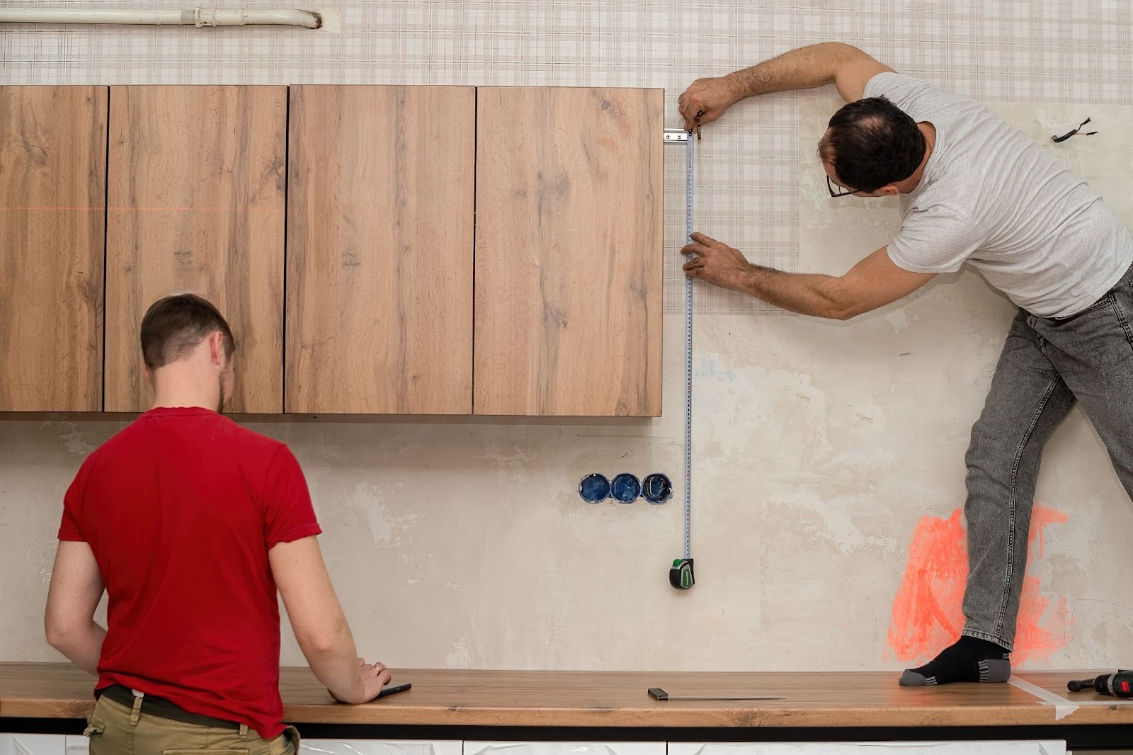 Two kitchen installation specialists measuring cabinetry for a modern kitchen remodel