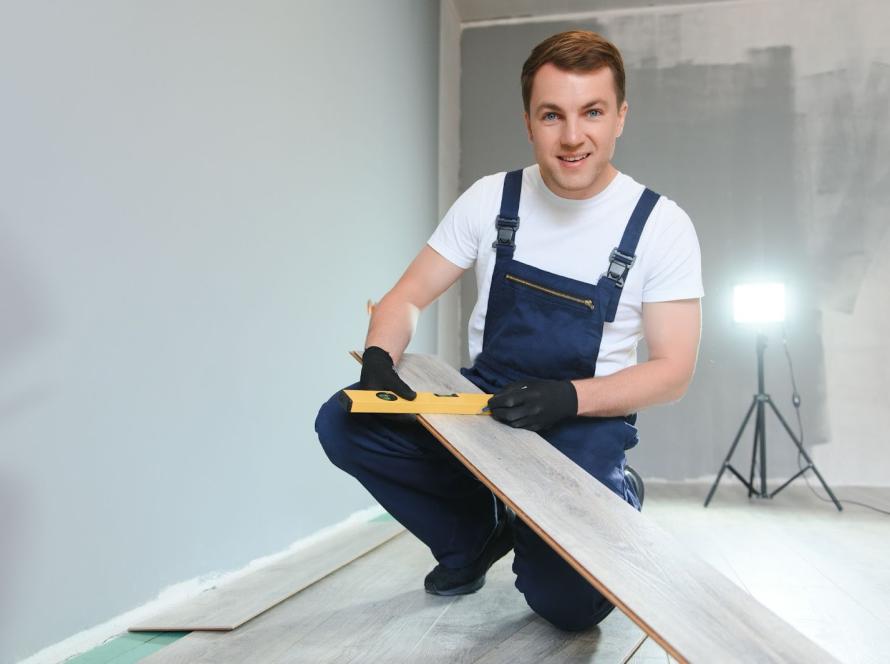 Flooring installer checking alignment with a level while getting ready to lay laminate planks
