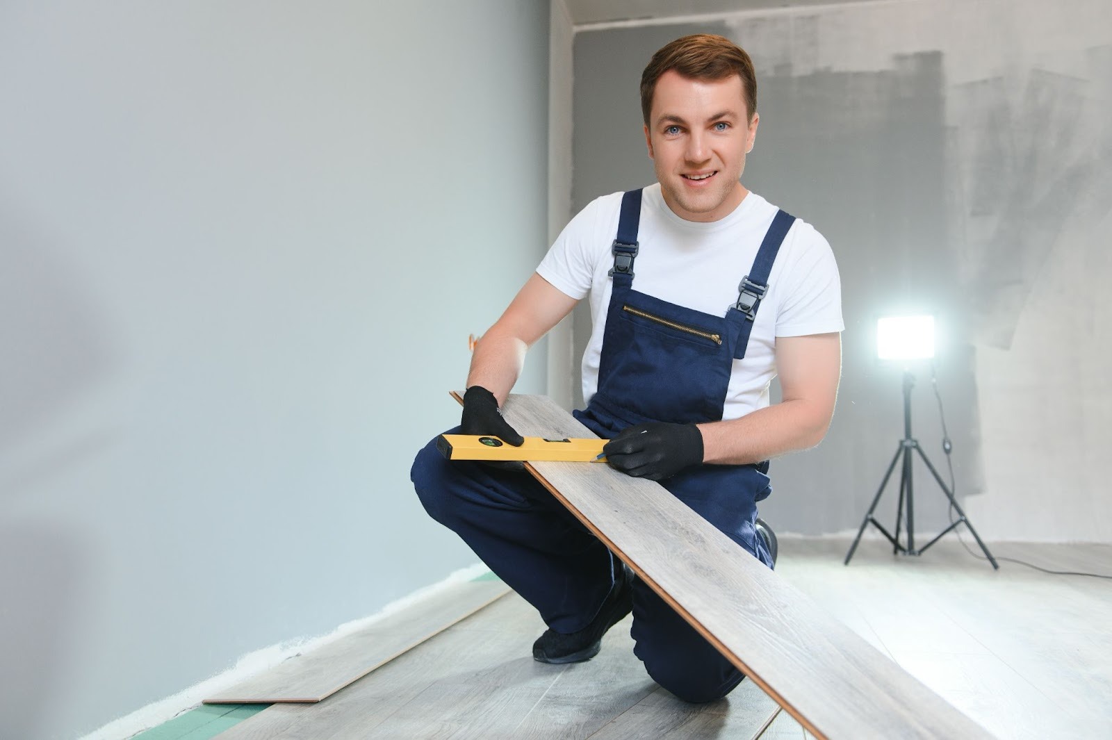 Flooring installer checking alignment with a level while getting ready to lay laminate planks