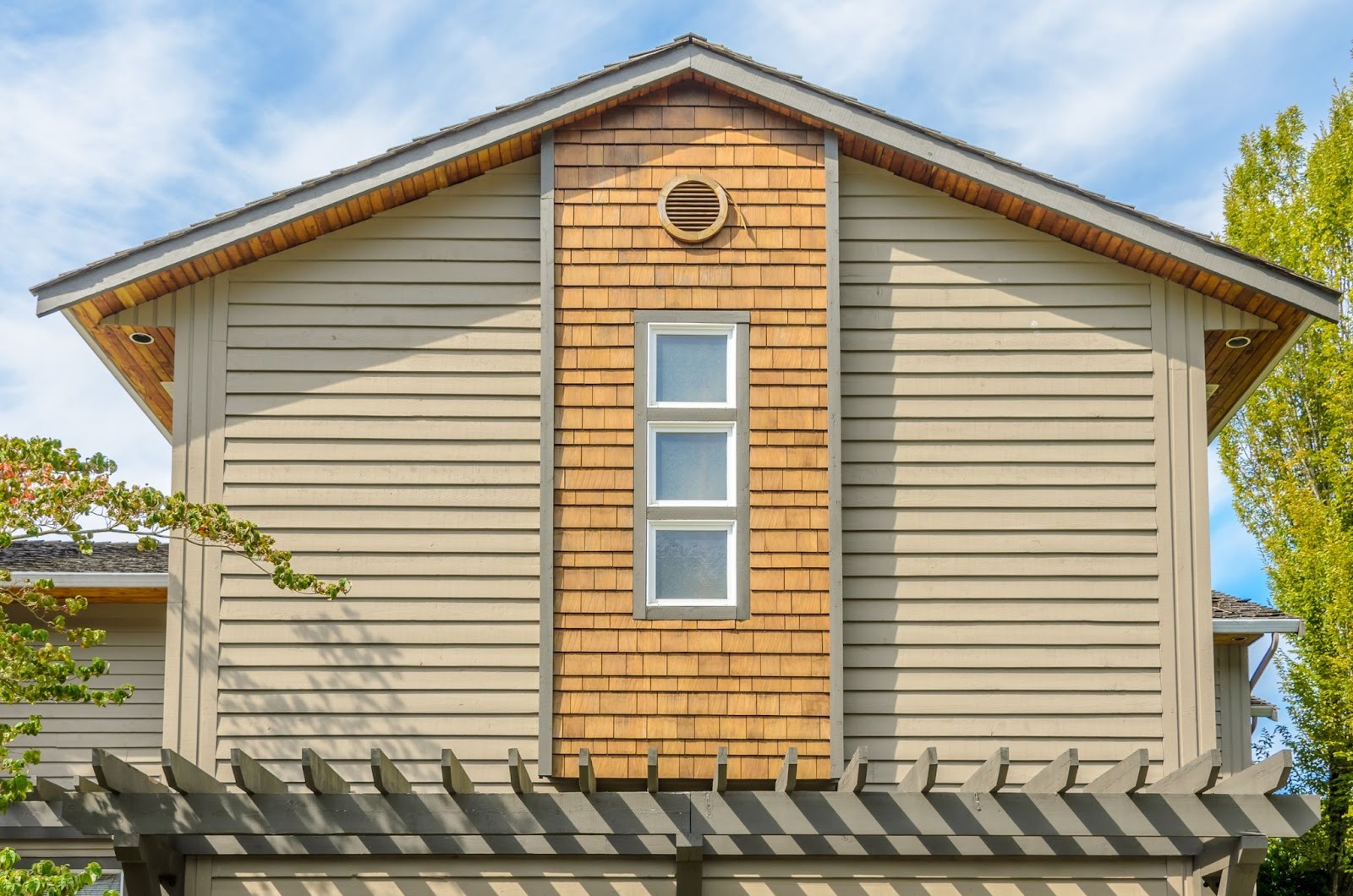 Upper exterior of a home featuring beige vinyl siding and clean white-framed windows