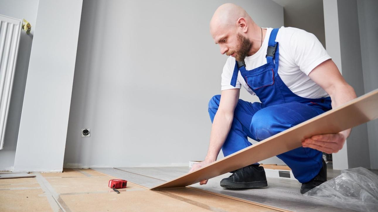 Professional flooring contractor laying laminate planks in a renovated living space
