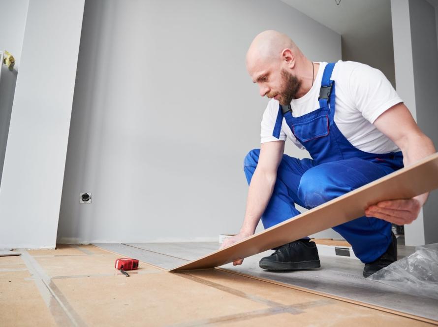 Professional flooring contractor laying laminate planks in a renovated living space
