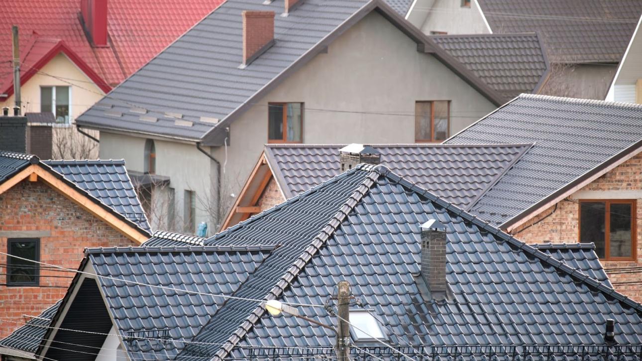Residential homes featuring metal roofing panels and ceramic tile shingles